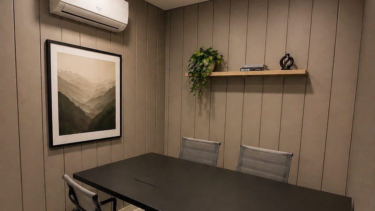 Sala privativa da unidade Executive com mesa escura, cadeiras cinza, painel ripado na parede e quadro de paisagem