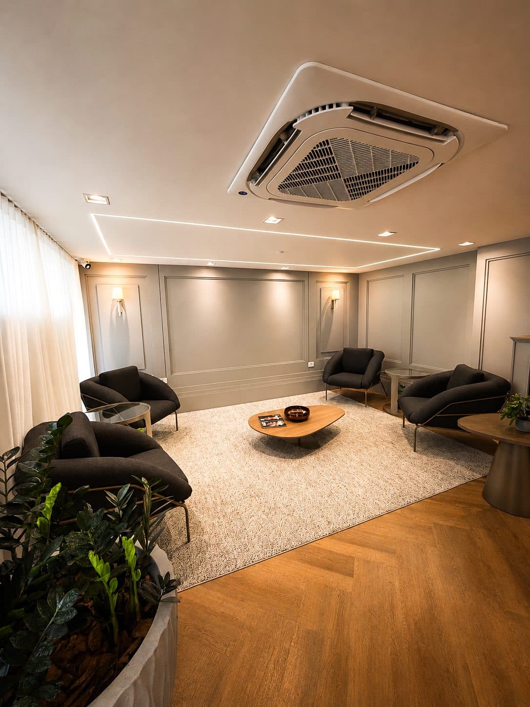 MYJOB Afonso Pena: lounge com poltronas escuras, tapete e piso de madeira