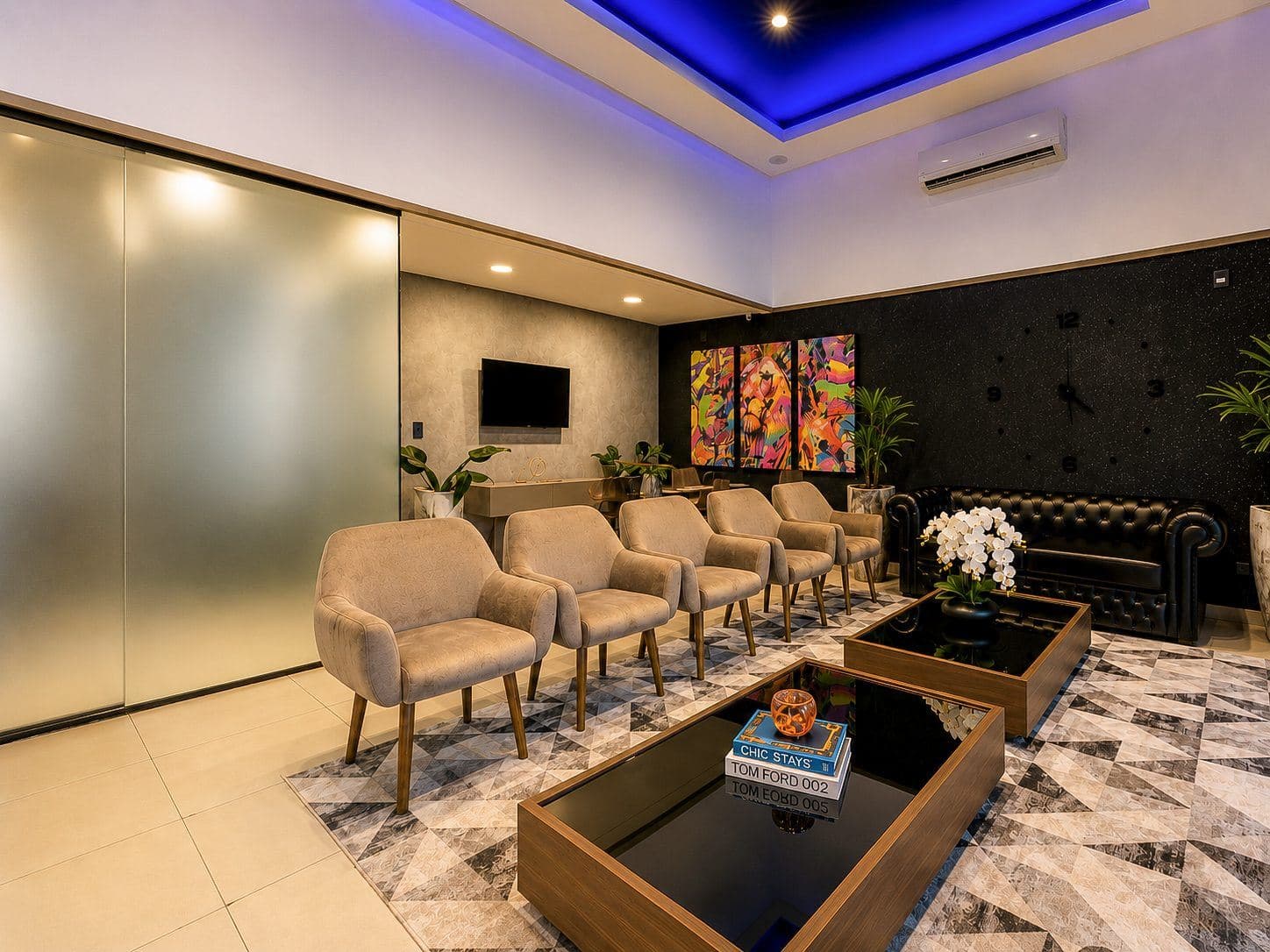 MYJOB Dourados: lounge com poltronas claras, sofá de couro capitonê, mesas de centro, quadros coloridos e teto com luz azul