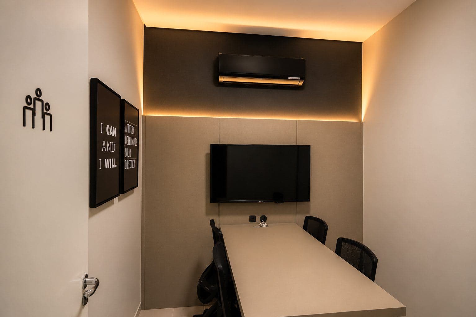 MYJOB Dourados: sala de atendimento com mesa, cadeiras pretas, TV e luz indireta no alto da parede