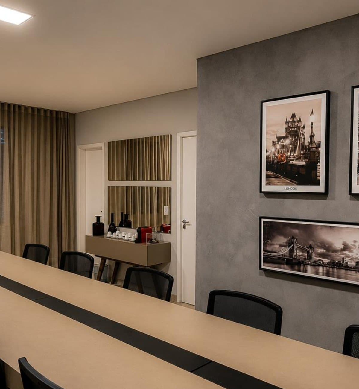 MYJOB Dourados: sala de reunião vista do outro lado, com parede cinza, quadros em preto e branco e aparador