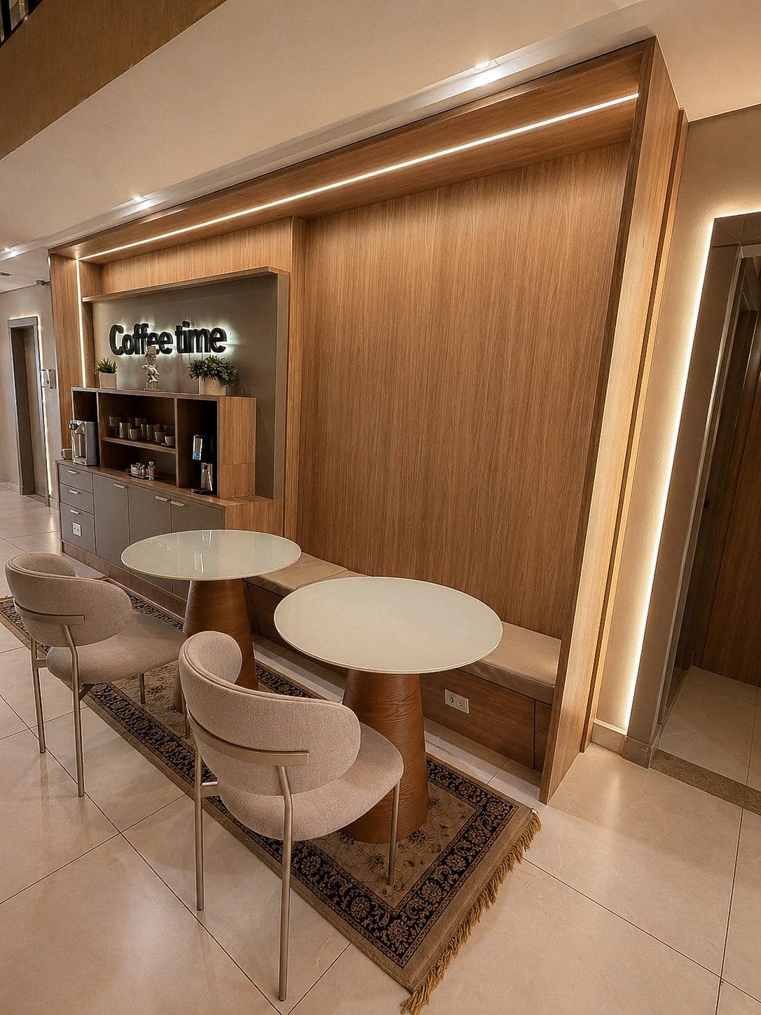 MYJOB Executive: área de café com duas mesas redondas, cadeiras claras e o painel Coffee time em madeira iluminada